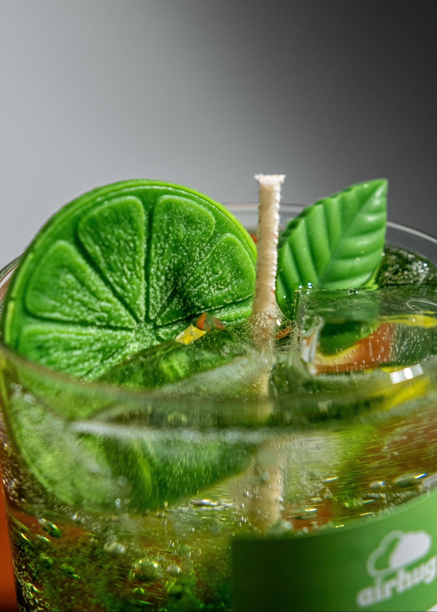 Close-up of a mint refresh candle with lime and mint leaves, featuring the Airhug brand.