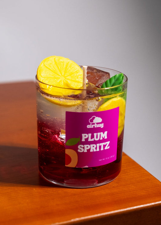 Glass of Plum Spritz dessert candle with a lemon slice on a wooden table